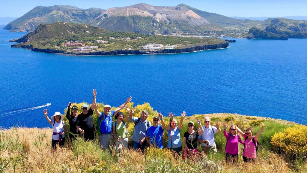 A Walk About Italy group waving on a trail above the sea in the Aeolian Islands